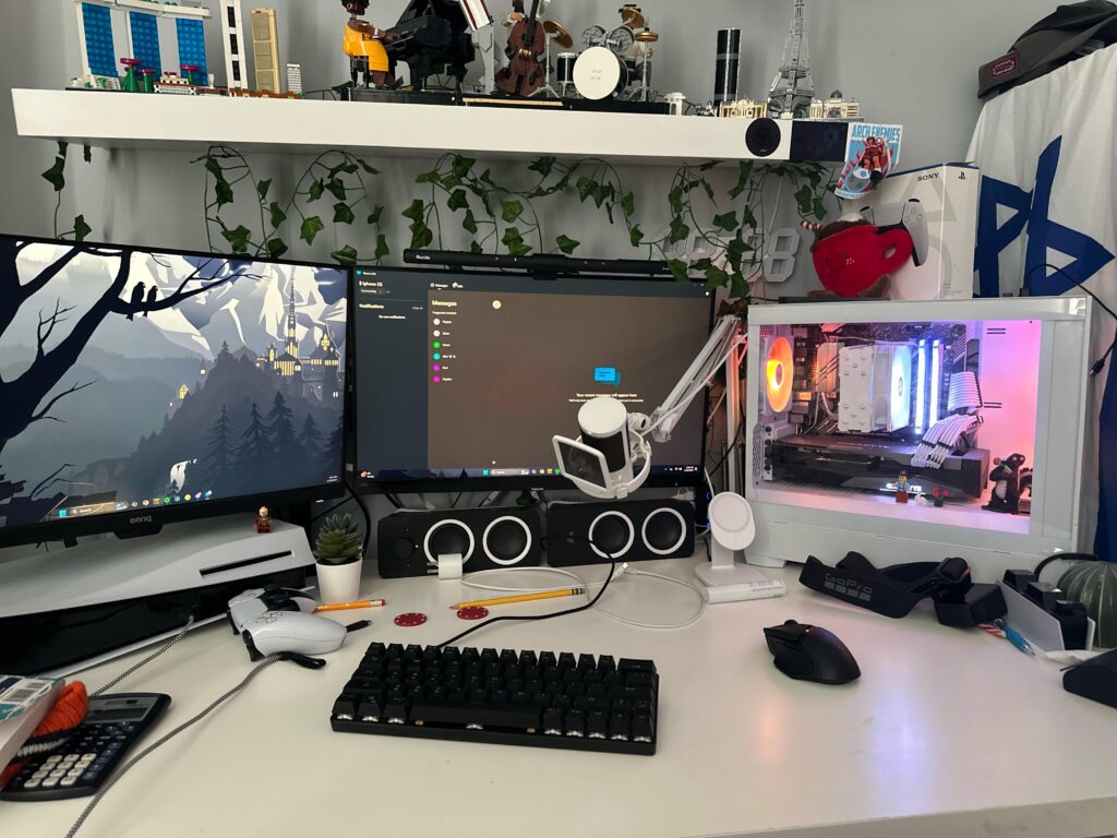 White-themed gaming and streaming setup with dual monitors, RGB gaming PC, LEGO decorations, and a PlayStation 5.