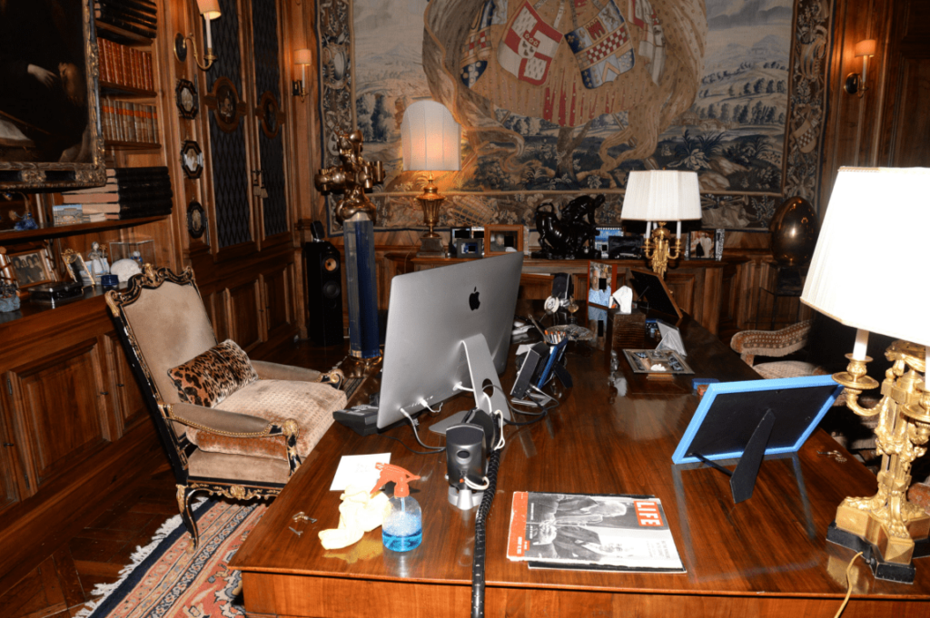 Luxurious wood-paneled office with ornate furniture, large wooden desk, and Apple desktop computer.