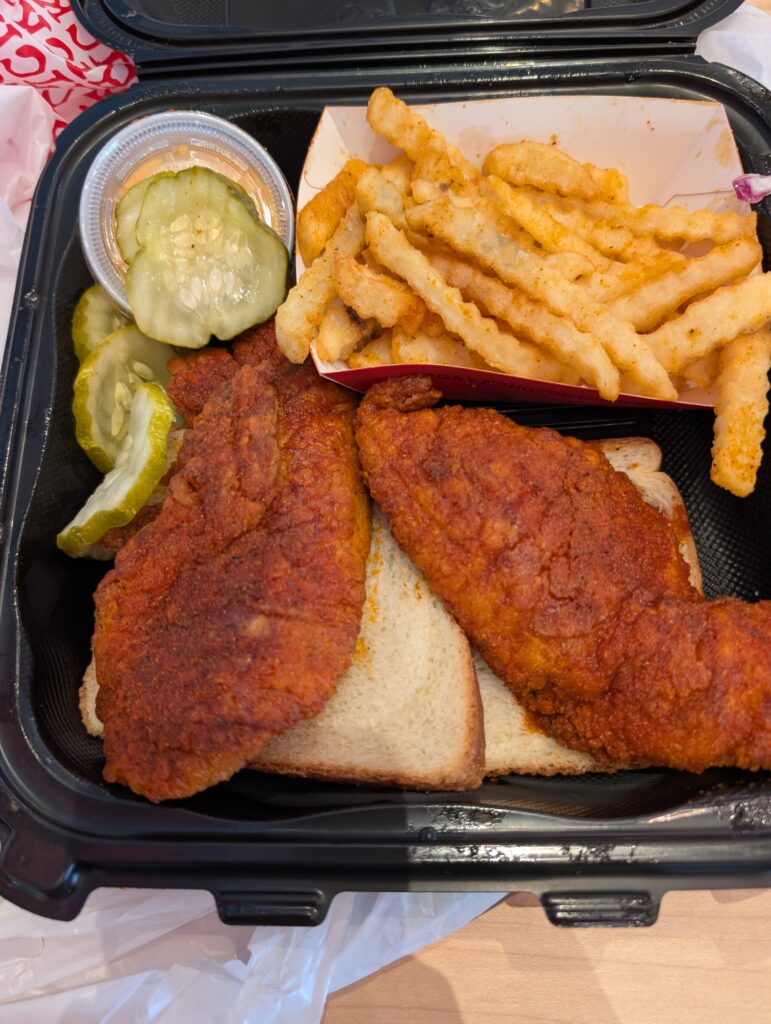 Dave’s Hot Chicken #1 combo with two chicken tenders, one Hot and one Medium, served on white bread with crinkle-cut fries and pickle slices.